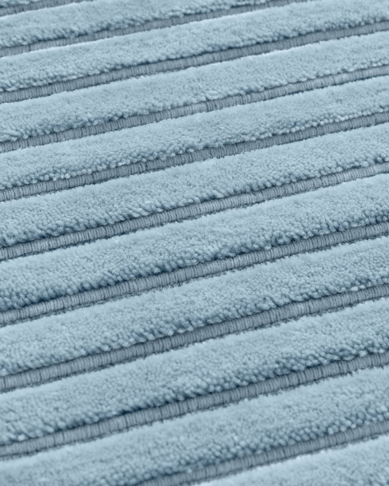 Close-up of the made-to-measure Park 02 rug in Sky, showing its round shape and linear loop and cut pile texture.